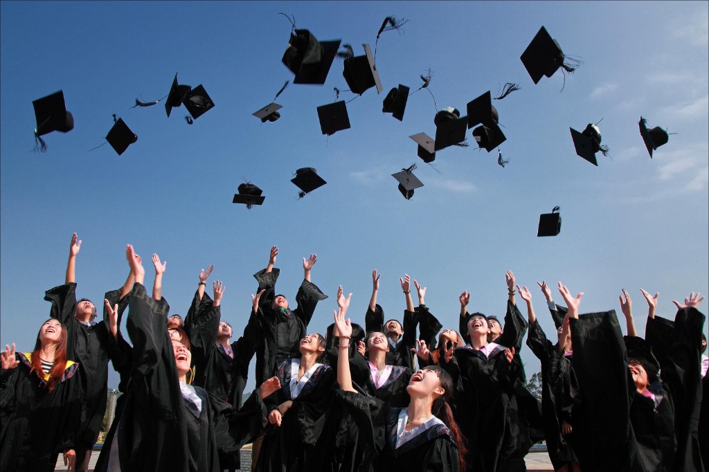 Graduates cheering and tossing graduation caps into the sky